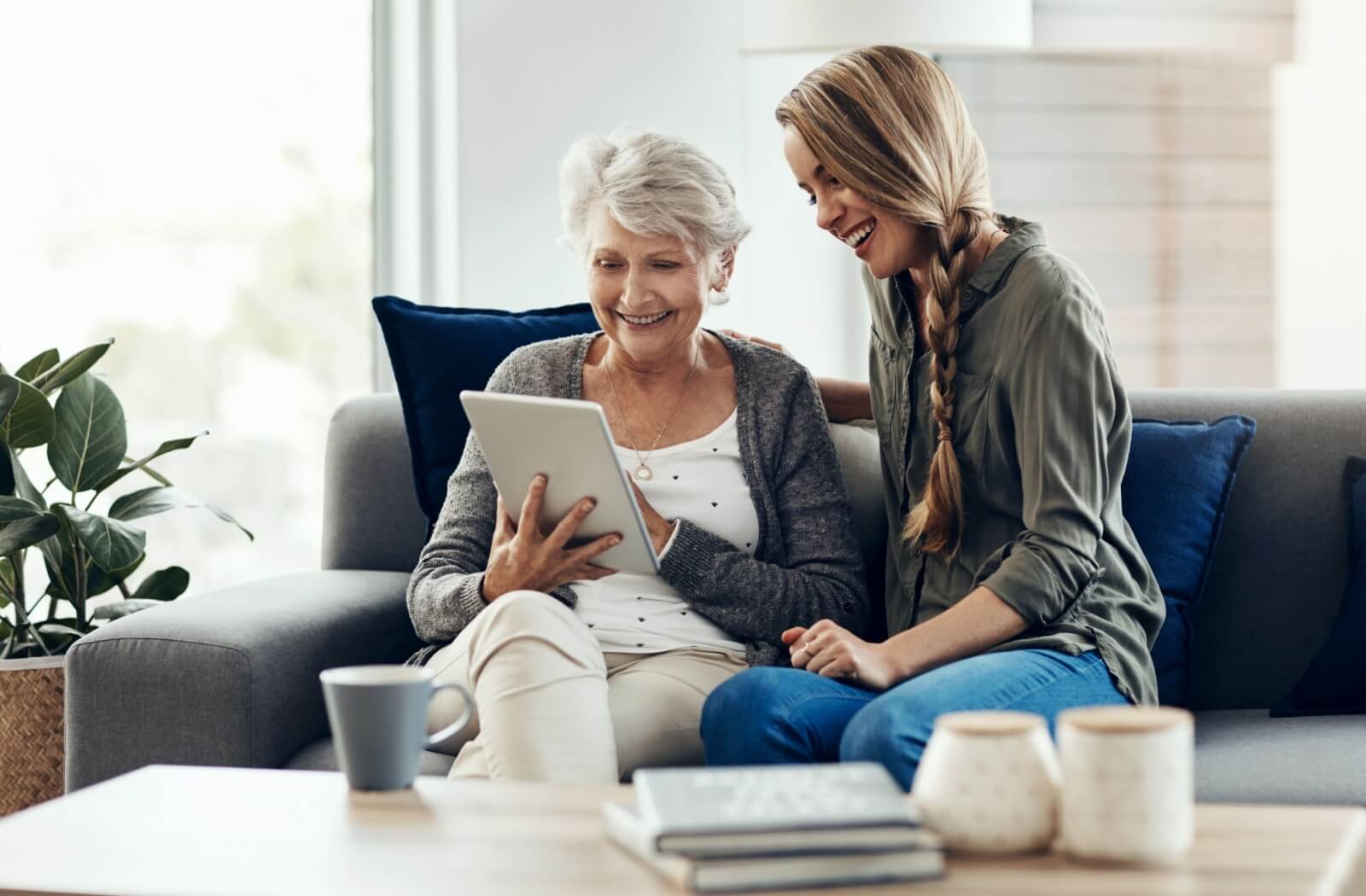 An adult and their senior parent look at memory care community options together on a tablet.
