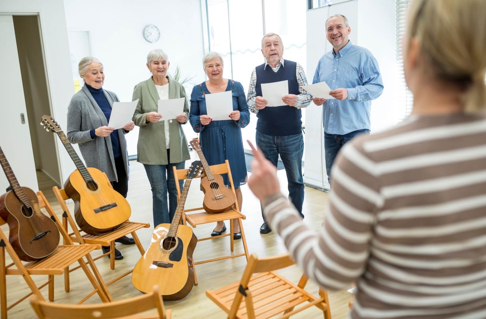 A group of happy seniors enjoy a music class together in their retirement community.
