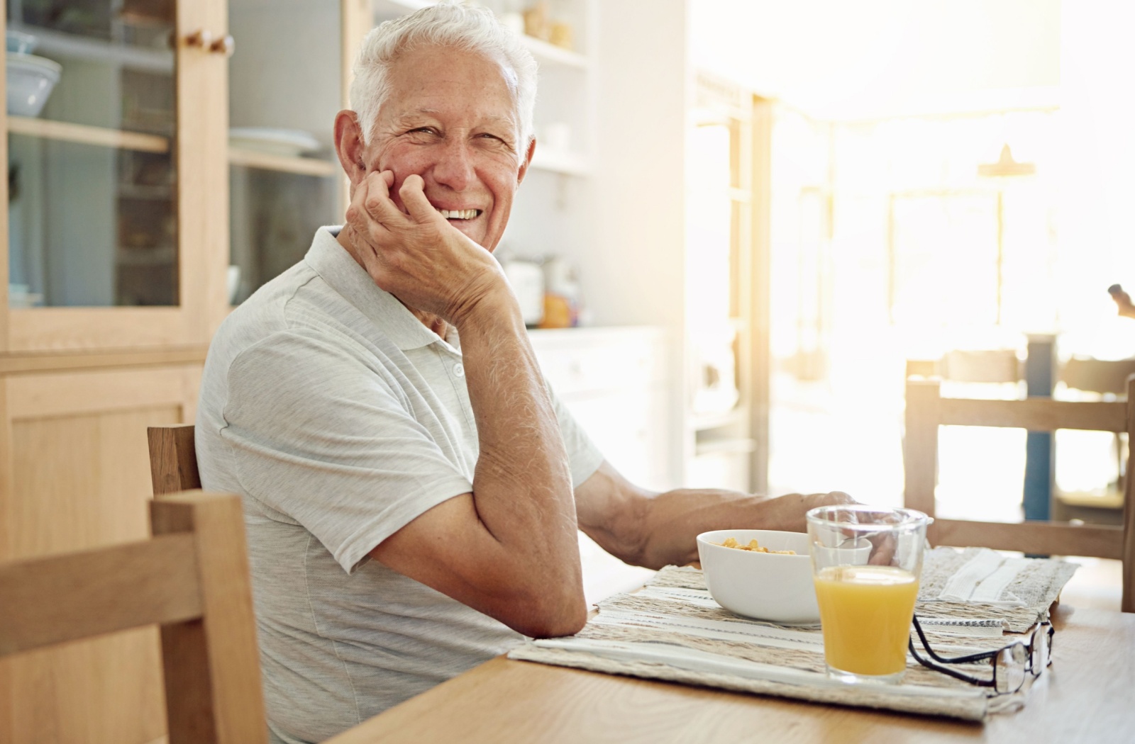 A happy senior enjoys a leisurely breakfast in his retirement community's dining area.