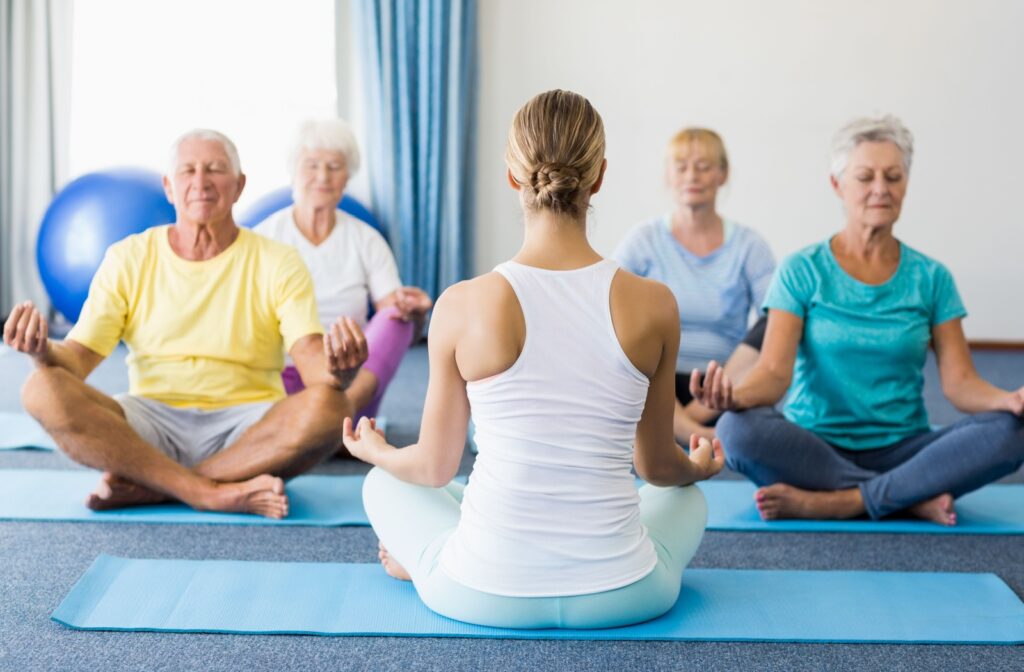 A gathering of seniors sat on their yoga mats, engaged in tranquil meditation as part of their yoga session.