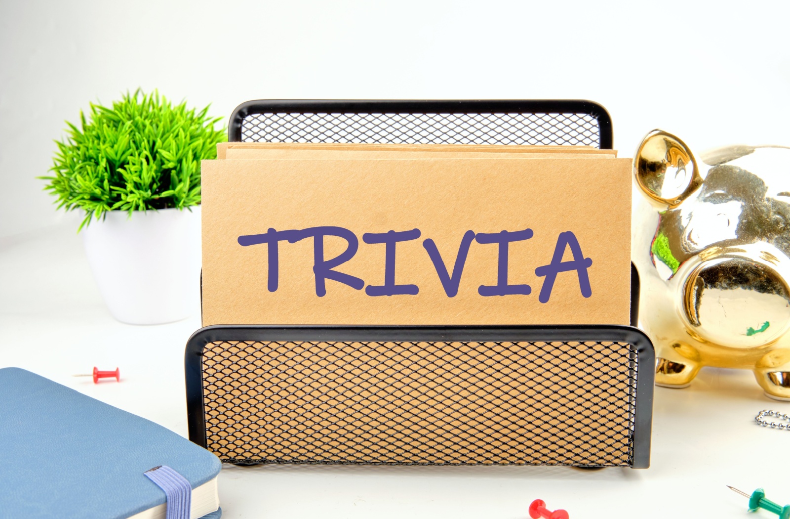 A close-up of an envelope with the word "TRIVIA" written on it, held up by a small black stand.